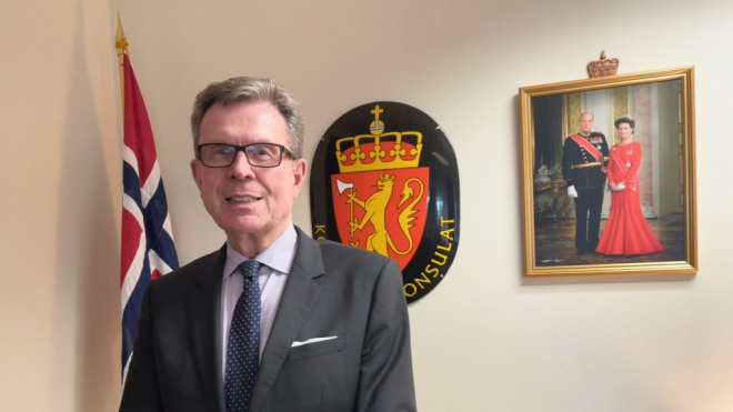 Michael Soroy in front of the Norway flag in the consulate